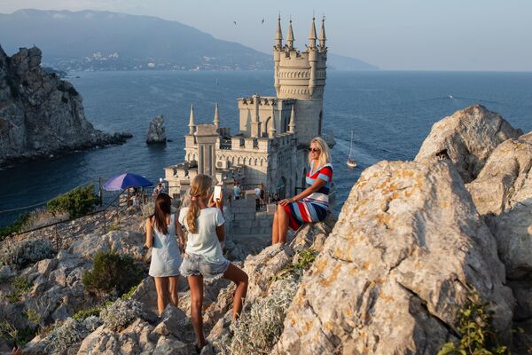Отдыхающие фотографируются возле замка Ласточкино гнездо на береговой скале в поселке Гаспра в Крыму Отдыхающие фотографируются возле замка Ласточкино гнездо на береговой скале в поселке Гаспра в Крыму