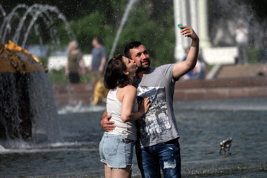 Молодые люди отдыхают у фонтана на ВДНХ в Москве Молодые люди отдыхают у фонтана на ВДНХ в Москве
