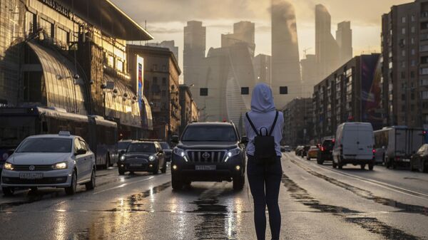 Девушка на пешеходном переходе на Кутузовском проспекте. На дальнем плане - небоскребы делового центра Москва-сити