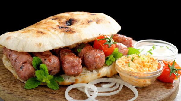 Чевапчичи на гриле с маринованным красным перцем и творожным сыром каймак, подается с лепешкой лепинья Чевапчичи на гриле с маринованным красным перцем и творожным сыром каймак, подается с лепешкой лепинья