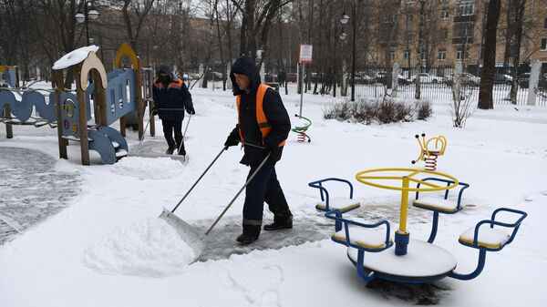Сотрудники коммунальной службы чистят детскую площадку от снега в Москве Сотрудники коммунальной службы чистят детскую площадку от снега в Москве
